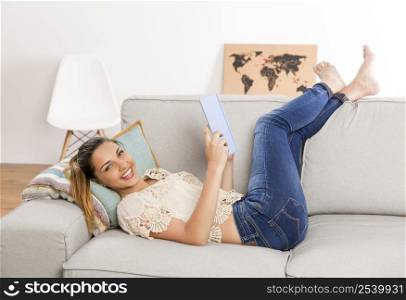 Beautiful woman at home sitting on the couch and reading a book