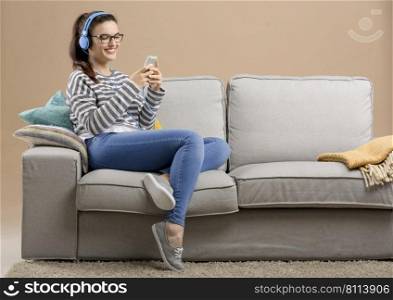 Beautiful woman at home sitting on the sofa and listen music