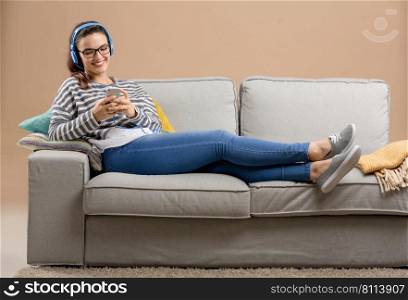 Beautiful woman at home sitting on the sofa and listen music