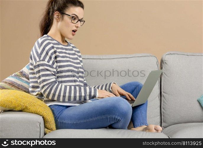Beautiful woman at home sitting on the sofa and working with a laptop