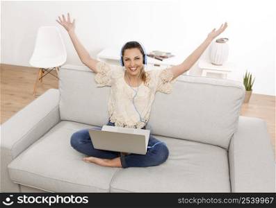Beautiful woman at home working on her laptop and listen music