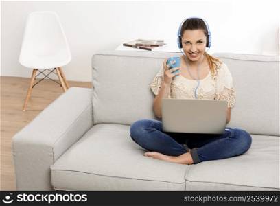 Beautiful woman at home working on her laptop and listening music