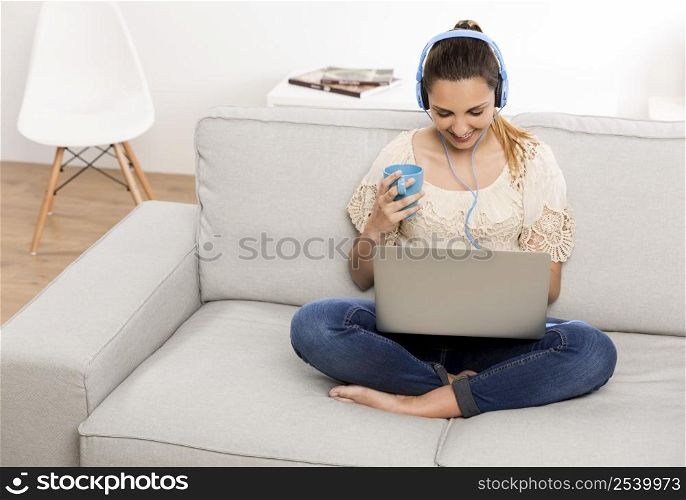 Beautiful woman at home working on her laptop and listening music