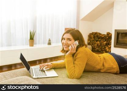 Beautiful woman at home working with a laptop and making a phone call