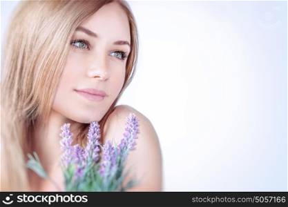 Beautiful woman at spa, closeup portrait of a nice blond girl enjoying aroma of a lavender flowers over clear background, using natural cosmetics, healthy lifestyle