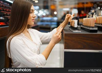 Beautiful woman at the shelf in cosmetics store, side view. Buyer at the showcase in luxury beauty shop salon, female customer in fashion market. Beautiful woman at the shelf in cosmetics store