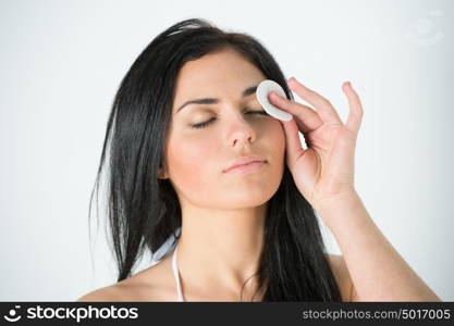 Beautiful woman cleaning her pretty face with cotton swab at her bathroom