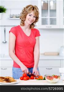 Beautiful woman cooking healthy food in the kitchen - indoors