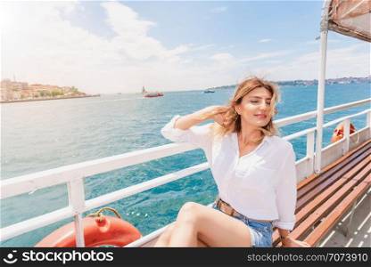 Beautiful woman cruises in a ferry with seascape view of Maidens Tower in Istanbul,Turkey. Beautiful woman in red dress travels on a ferry in Istanbul