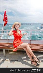 Beautiful woman cruises in a ferry with view of Turkish flag and Istanbul Bosphorus in Turkey. Beautiful woman travels with ferry between Asia and Europe