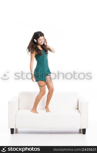 Beautiful woman dancing and jumping over the sofa, isolated in white