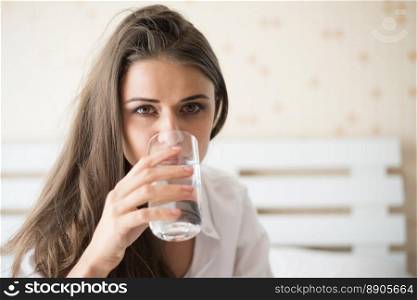 Beautiful woman drinking fresh water in the bed at the morning