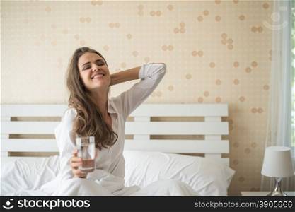 Beautiful woman drinking fresh water in the bed at the morning