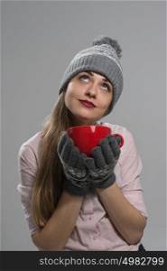 Beautiful woman drinking hot drink wearing winter clothes and planning