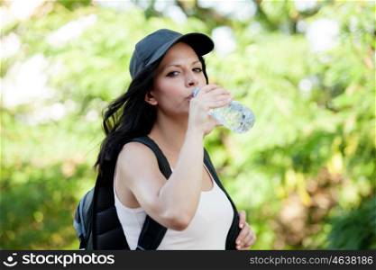 Beautiful woman drinking water while hiking through the countryside