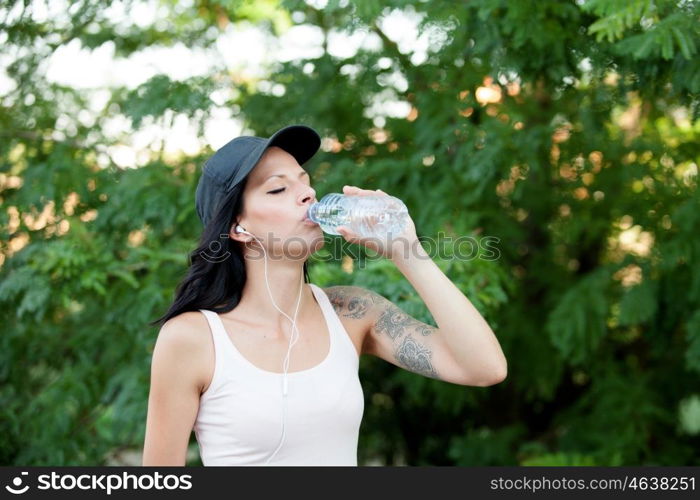 Beautiful woman drinking water while hiking through the countryside