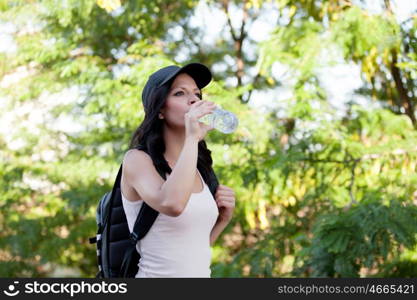 Beautiful woman drinking water while hiking through the countryside