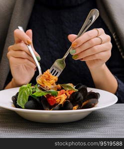 beautiful woman eating pasta with mussels in a restaurant