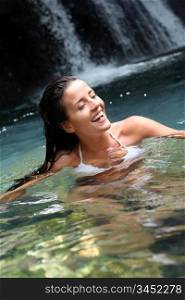 Beautiful woman enjoying bathing near natural waterfall