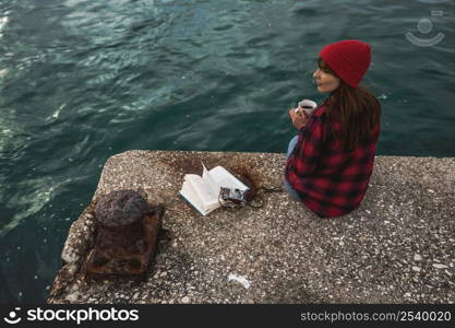 Beautiful woman enjoying her day in the lake with a mug of hot coffee