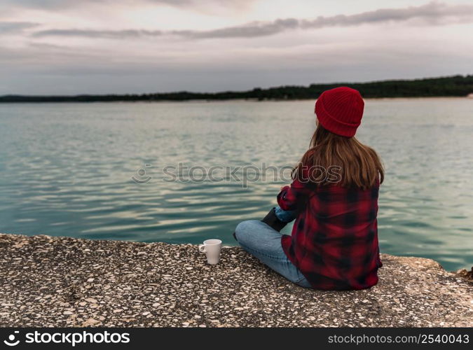 Beautiful woman enjoying her day in the lake with a mug of hot coffee