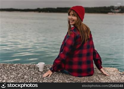 Beautiful woman enjoying her day in the lake with a mug of hot coffee