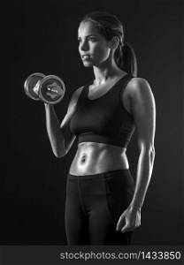 Beautiful woman exercising her bicep muscles with a dumbbell.