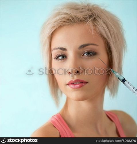 Beautiful woman gets an injection in her face on blue background