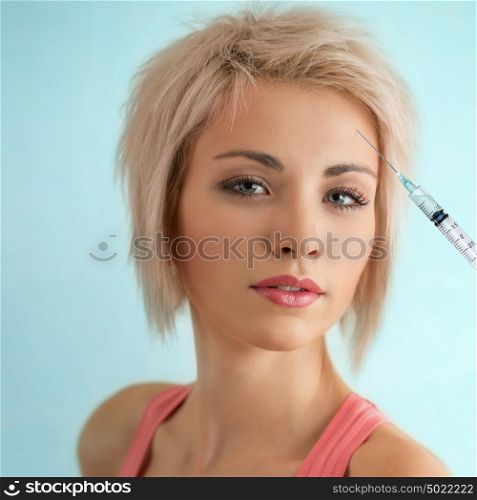 Beautiful woman gets an injection in her face on blue background