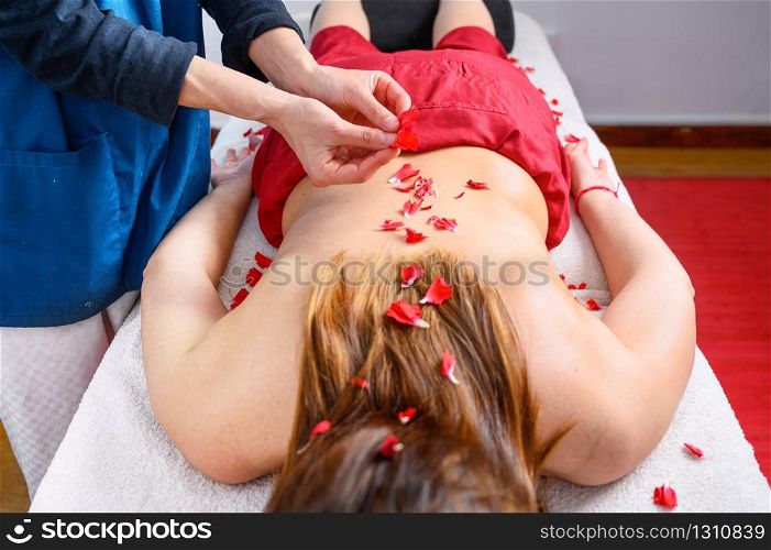 Beautiful woman getting massage and spa treatment with flower petals in spa salon .. Beautiful woman getting massage and spa treatment with flower petals in spa salon.