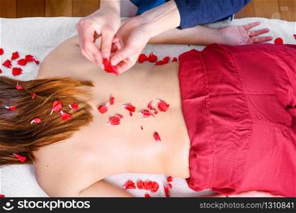 Beautiful woman getting massage and spa treatment with flower petals in spa salon .. Beautiful woman getting massage and spa treatment with flower petals in spa salon.