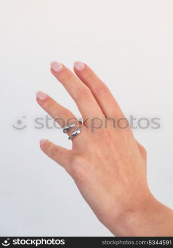 Beautiful woman hand with Bold Adjustable Silver Ring set against a white background. Romantic composition. Beautiful valentine&rsquo;s gift.