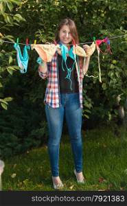 Beautiful woman hanging swimsuits on clothesline at garden