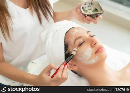 Beautiful woman having a facial cosmetic scrub treatment from professional dermatologist at wellness spa. Anti-aging, facial skin care and luxury lifestyle concept.. Beautiful woman having a facial treatment at spa.