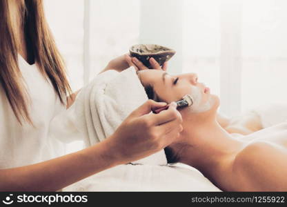Beautiful woman having a facial cosmetic scrub treatment from professional dermatologist at wellness spa. Anti-aging, facial skin care and luxury lifestyle concept.