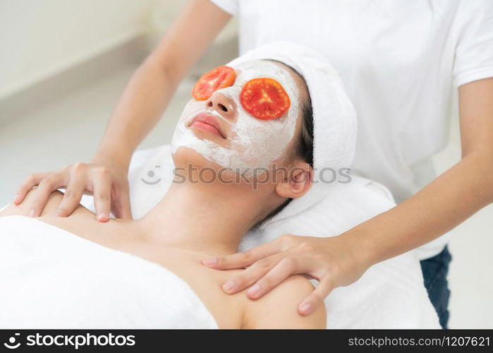 Beautiful woman having a facial mask treatment with tomato cream extract showing benefit of nature treatment. Anti-aging cosmetology, facial skin care and luxury lifestyle concept.. Woman get facial mask with tomato cream extract.