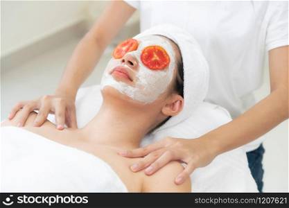 Beautiful woman having a facial mask treatment with tomato cream extract showing benefit of nature treatment. Anti-aging cosmetology, facial skin care and luxury lifestyle concept.. Woman get facial mask with tomato cream extract.