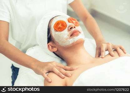 Beautiful woman having a facial mask treatment with tomato cream extract showing benefit of nature treatment. Anti-aging cosmetology, facial skin care and luxury lifestyle concept.