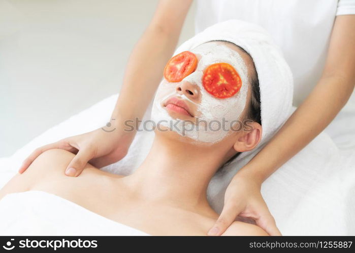 Beautiful woman having a facial mask treatment with tomato cream extract showing benefit of nature treatment. Anti-aging cosmetology, facial skin care and luxury lifestyle concept.