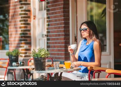 Beautiful woman having breakfast at outdoor cafe. Woman having breakfastin outdoor restaraunt
