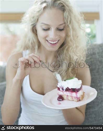 Beautiful woman having raspberry cake in house