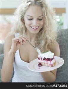 Beautiful woman having raspberry cake in house
