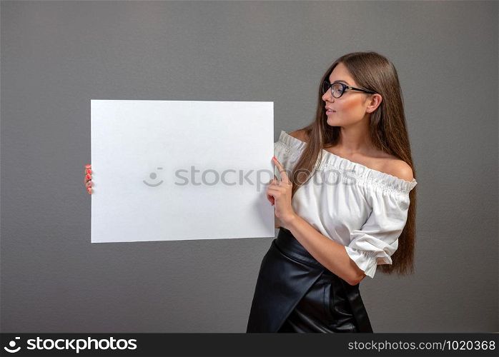Beautiful woman holding a blank billboard isolated on gray background.