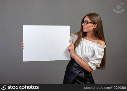 Beautiful woman holding a blank billboard isolated on gray background.