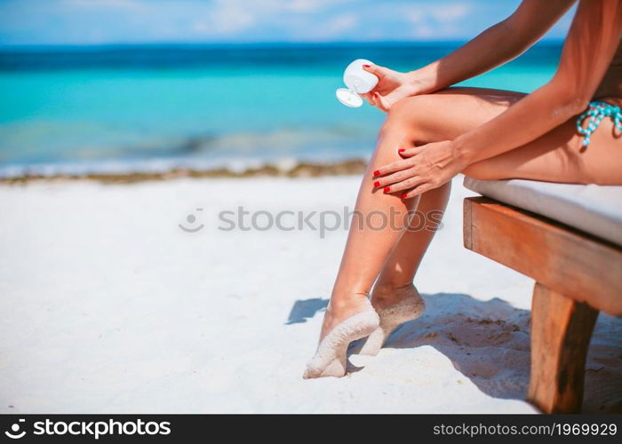 Beautiful woman holding a suncream on a tropical beach. Beautiful young woman holding a suncream lying on tropical beach