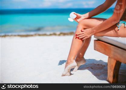 Beautiful woman holding a suncream on a tropical beach. Beautiful young woman holding a suncream lying on tropical beach