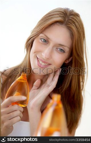 Beautiful woman holding bottle of perfume