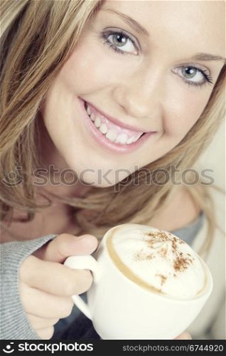Beautiful woman holding cup of coffee and smiling