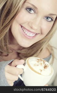 Beautiful woman holding cup of coffee and smiling