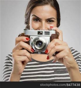 Beautiful woman holding her vintage camera over the face
